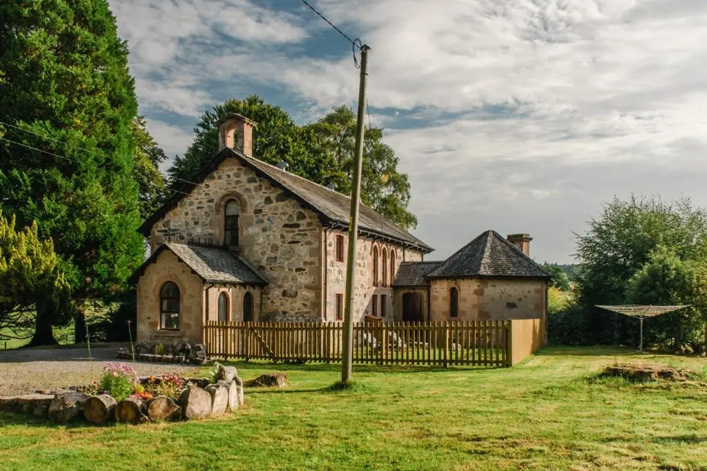 an old stone church with a fence in front of it at Beautiful Character House in Muir of Ord in Muir of Ord