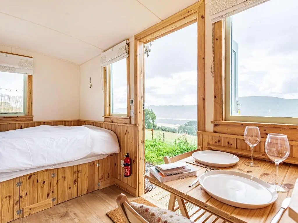 a bedroom with a bed and a table with wine glasses at Woodside Hut 3 - Uk36107 in Auchterneed