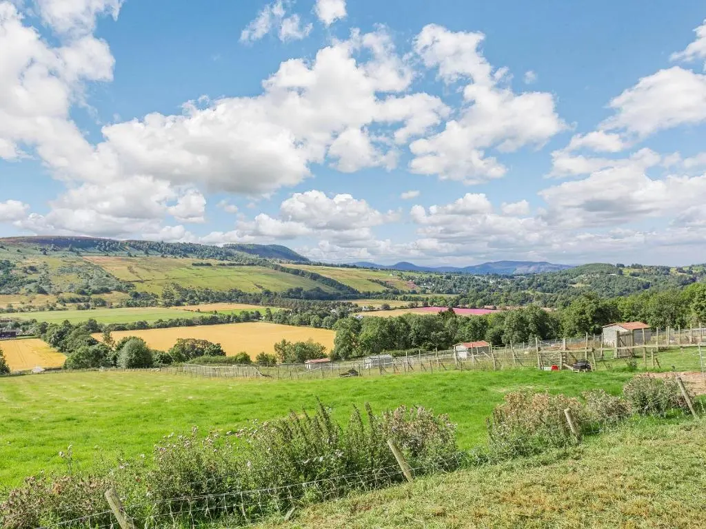 a field of green grass with mountains in the background at Woodside Hut 2 - Uk36106 in Auchterneed