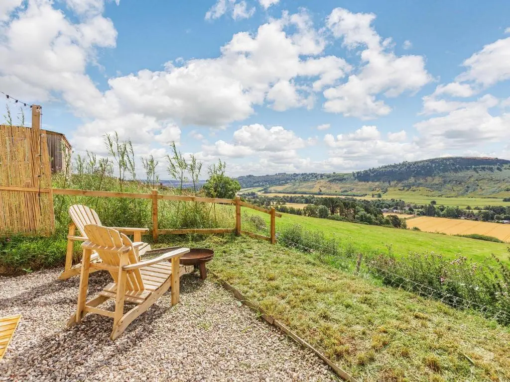 a wooden chair and a bench sitting on a patio at Woodside Hut 1 - Uk36105 in Auchterneed