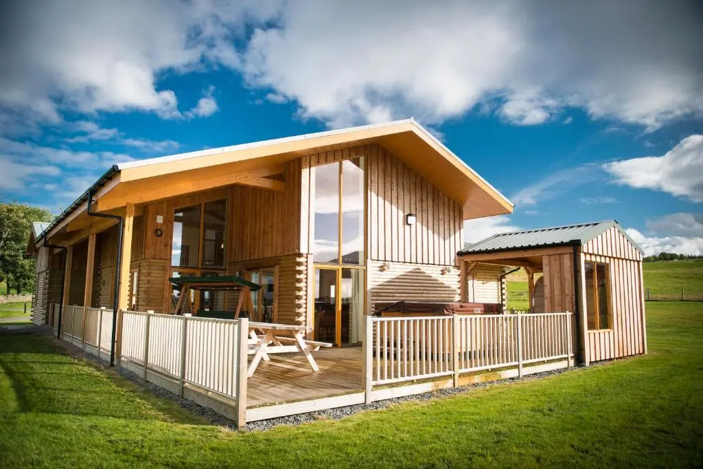 a wooden house with a deck and a fence at Blue Sky Lodges. Atlas & Aurae in Croy