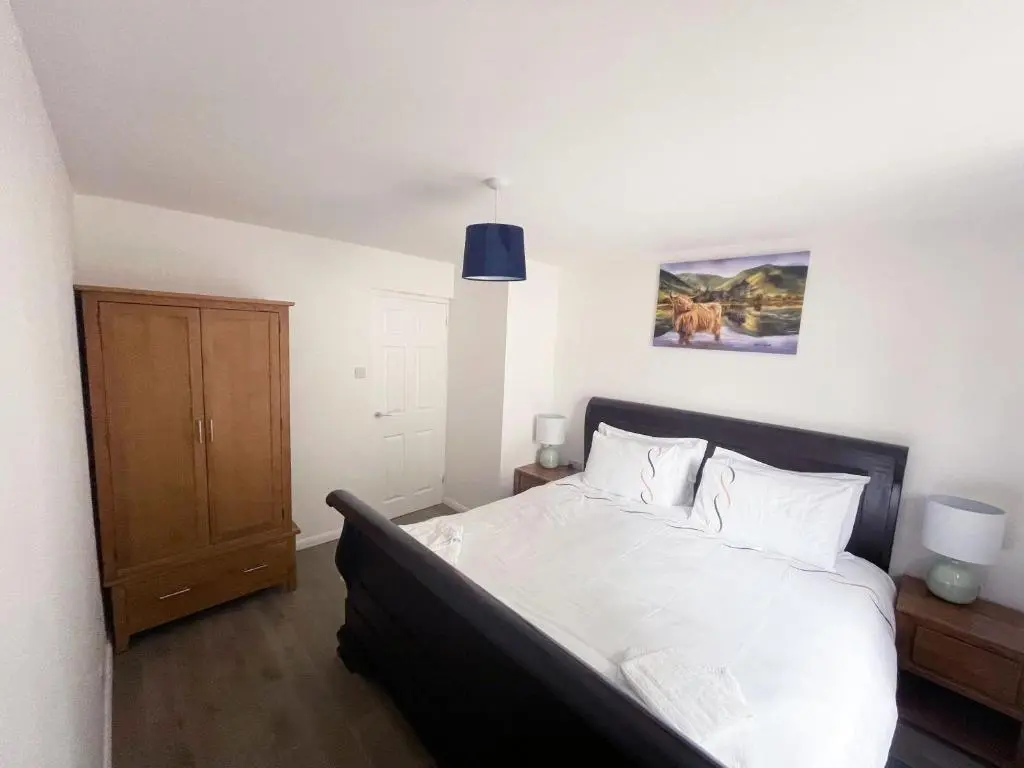a bedroom with a large bed with white sheets at Matara House Holiday Home in Inverness