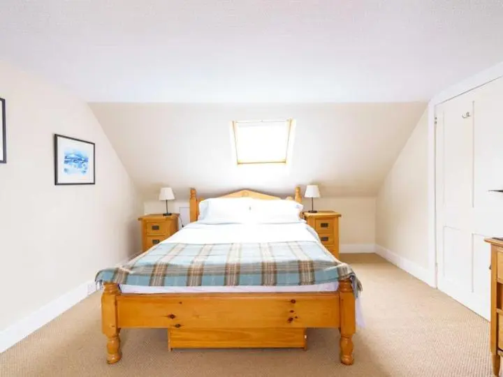 a bedroom with a wooden bed in a attic at Milne's Brae, cosy, comfortable and centrally located in beautiful Braemar in Braemar