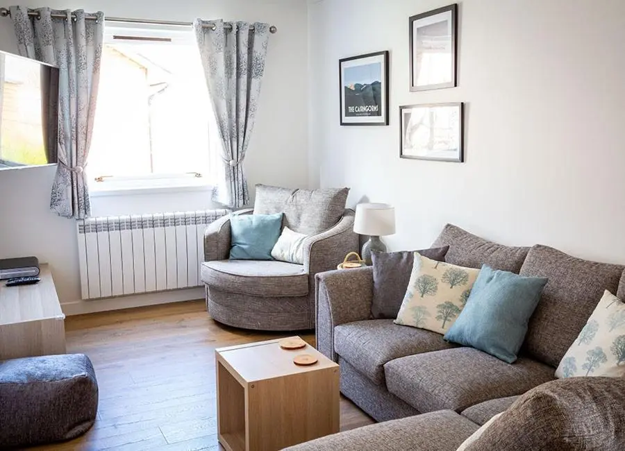 a living room with two couches and a table at Croftwood Cottage in Boat of Garten