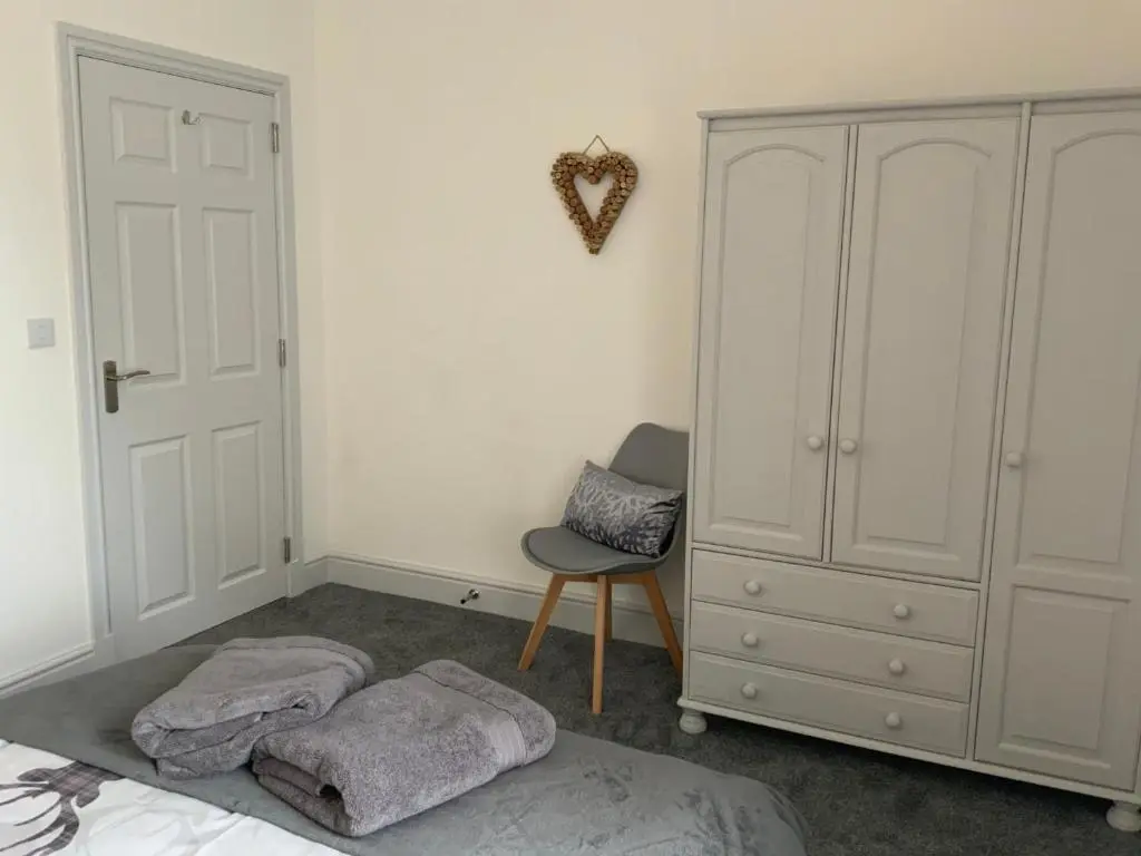 a bedroom with a bed and a cabinet and a chair at Deeside Snugs Apartments in Kincardine O\u02bcNeil