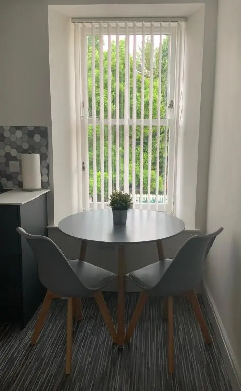 a table and chairs in a room with a window at Deeside Snugs Apartments in Kincardine O\u02bcNeil