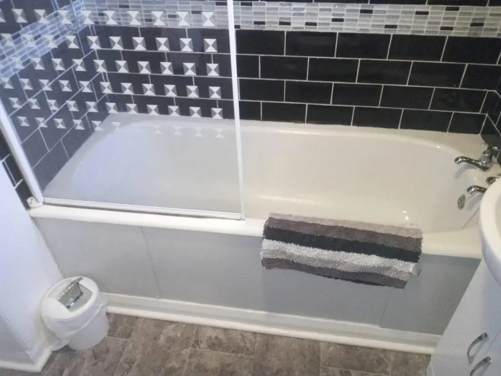 a bathroom with a bath tub with a sink and a toilet at 3-Bed House Sleeps 5 5 min walk from City Centre in Inverness