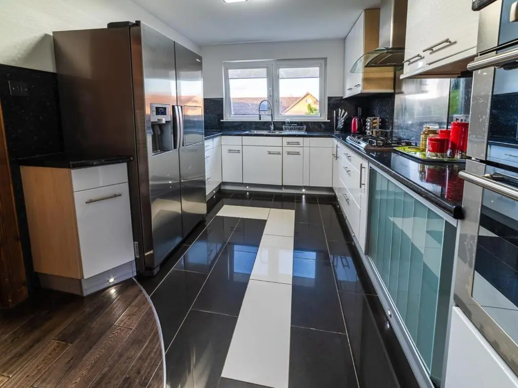 a large kitchen with stainless steel appliances and wooden floors at Willa , Cosy house in Inverness in Inverness