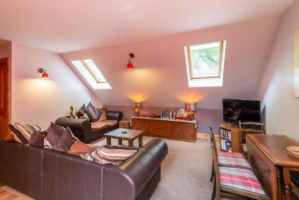 a living room with a leather couch and a tv at The Beeches Studio, Highlands of Scotland in Newtonmore