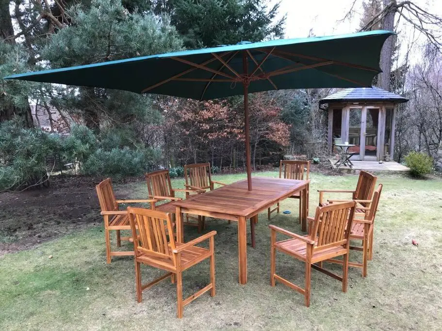 a wooden table and chairs with a green umbrella at The Beeches Studio, Highlands of Scotland in Newtonmore