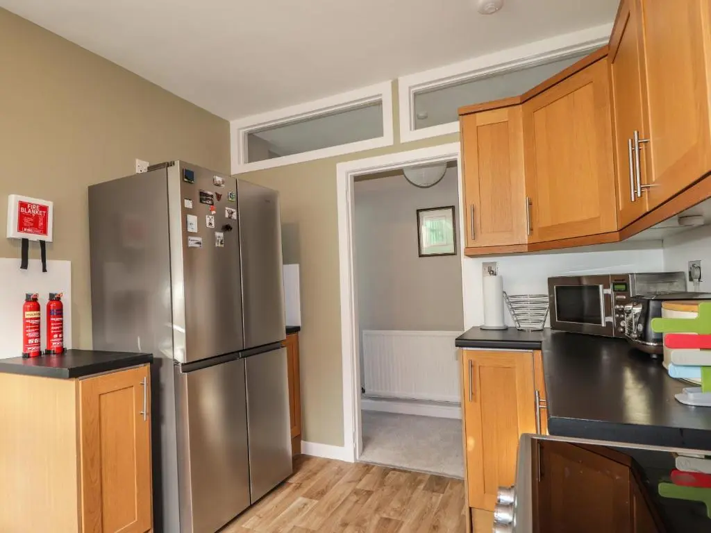 a kitchen with a stainless steel refrigerator and wooden cabinets at 62 Society Street in Nairn