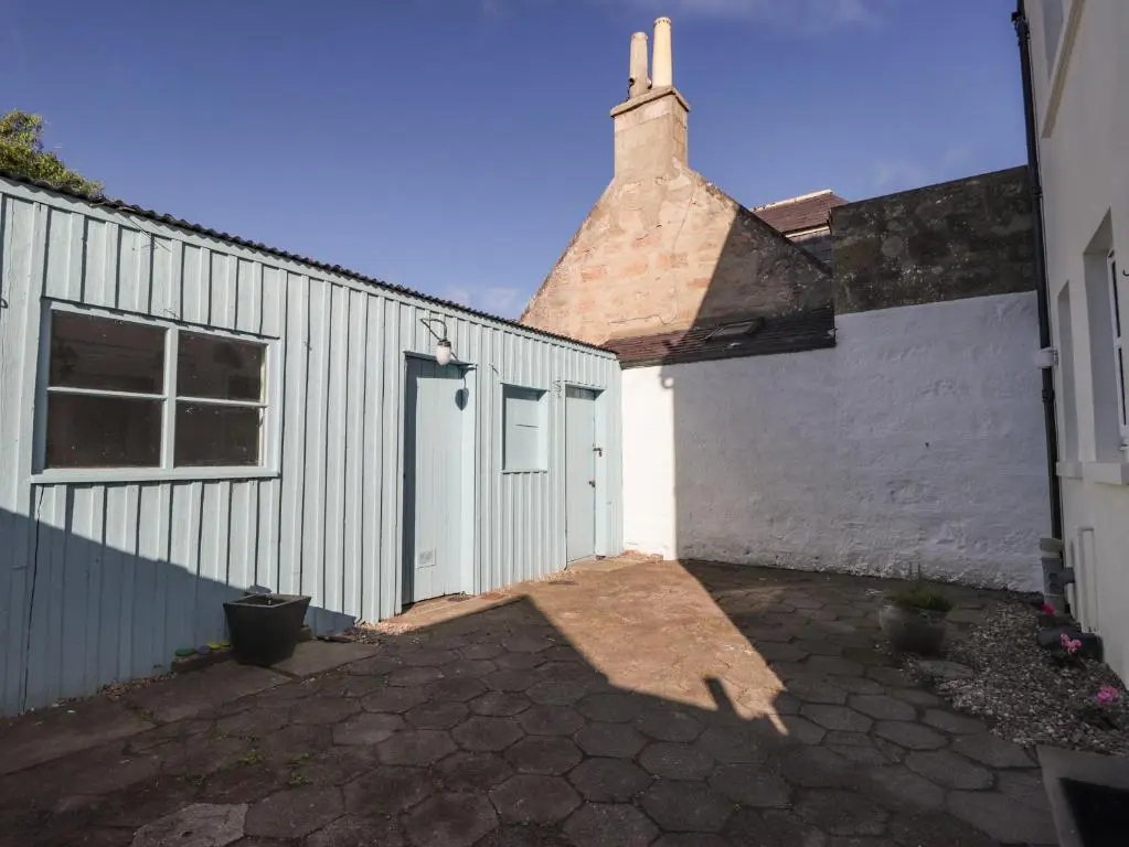 a white garage with a brick building next to it at 62 Society Street in Nairn