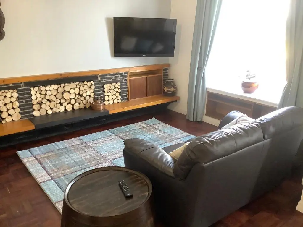 a living room with a leather couch and a television at Harbour View in Wick