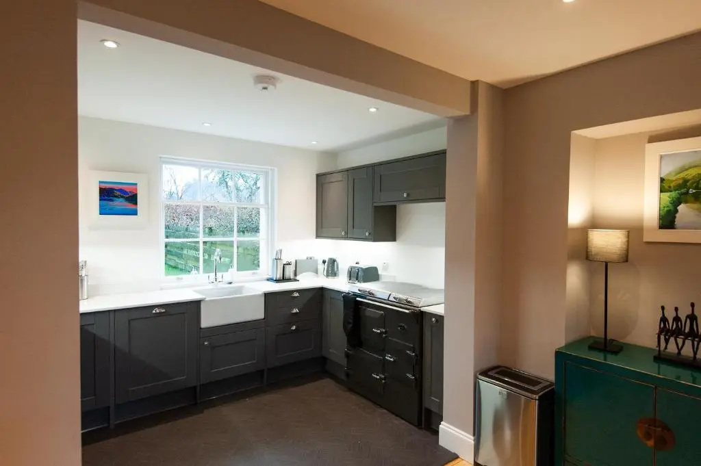 a kitchen with black cabinets and a window at Parkside, The Loch Ness Cottage Collection in Inverness