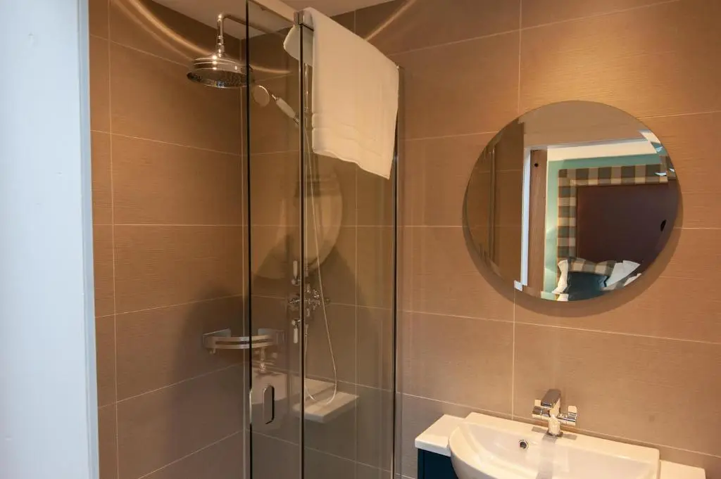 a bathroom with a shower and a sink and a mirror at Parkside, The Loch Ness Cottage Collection in Inverness