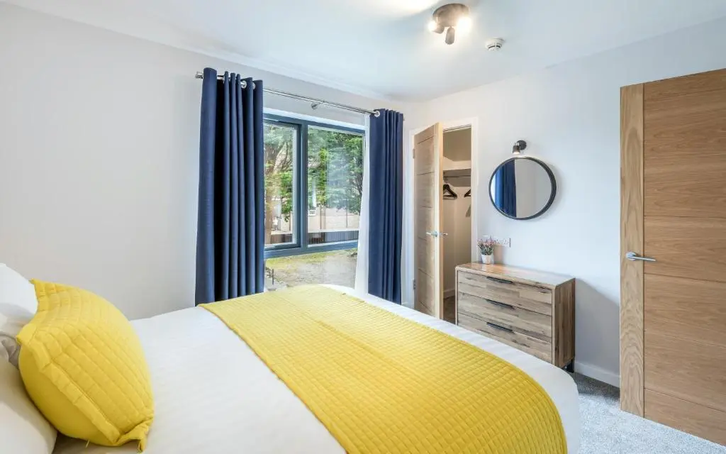 a bedroom with a yellow bed and a window at High Range Holiday Apartments in Aviemore