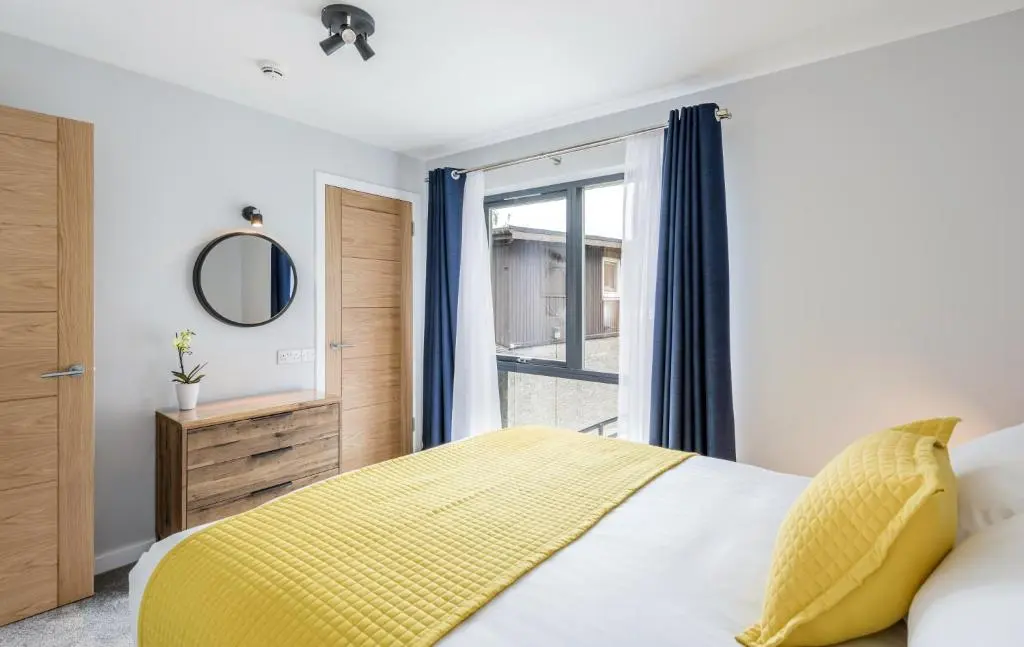 a bedroom with a yellow bed and a window at High Range Holiday Apartments in Aviemore