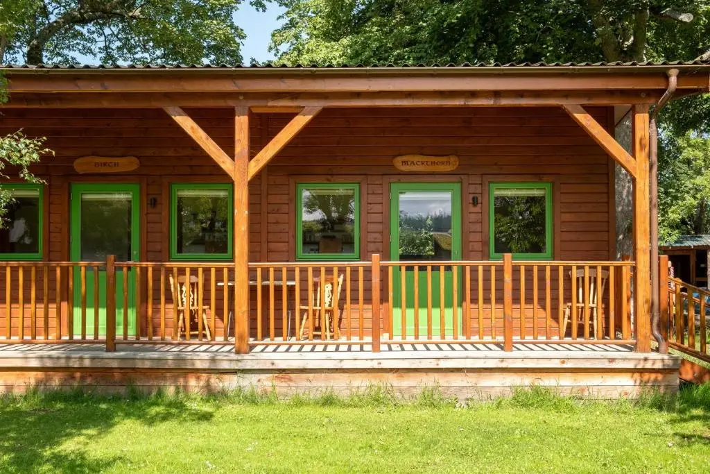 a log cabin with chairs on the porch at Marcassie Farm Lodges - Birch Studio in Forres