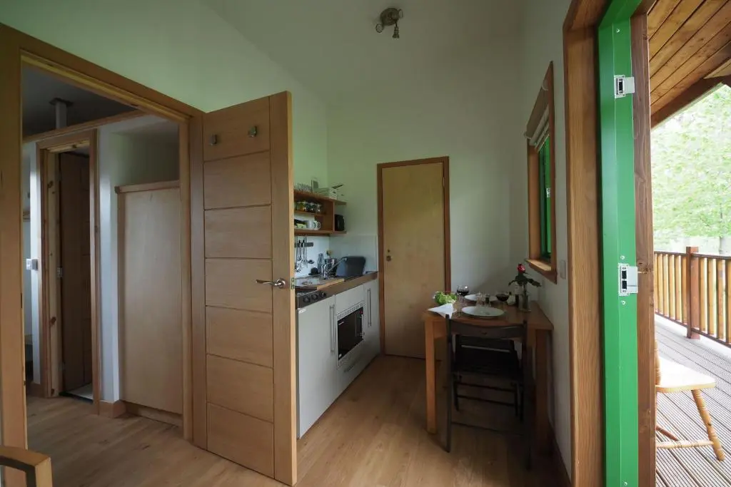 a kitchen with a table and a door to a room at Marcassie Farm Lodges - Birch Studio in Forres