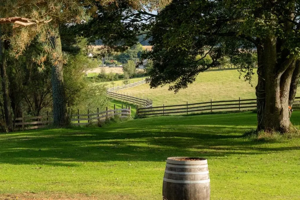 a barrel in a field with a fence and a tree at Marcassie Farm Lodges - Oak Studio - Accessible in Forres