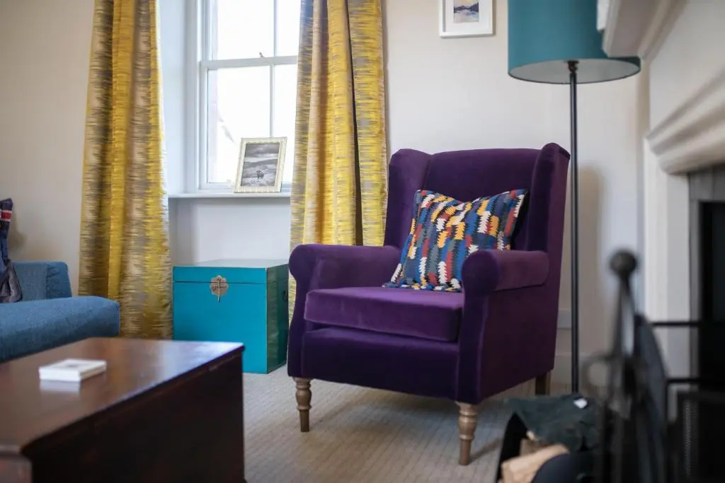 a purple chair with a pillow in a living room at The Cottage, The Loch Ness Cottage Collection in Inverness