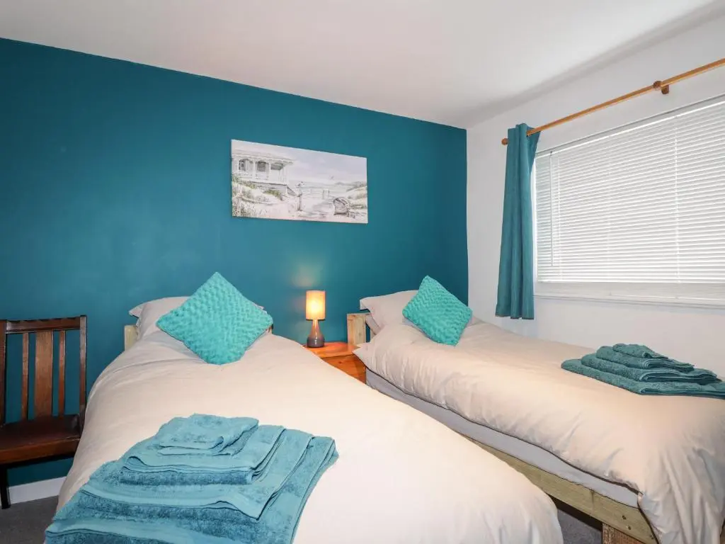 two beds in a room with blue walls at Griffin Cottage in Nairn