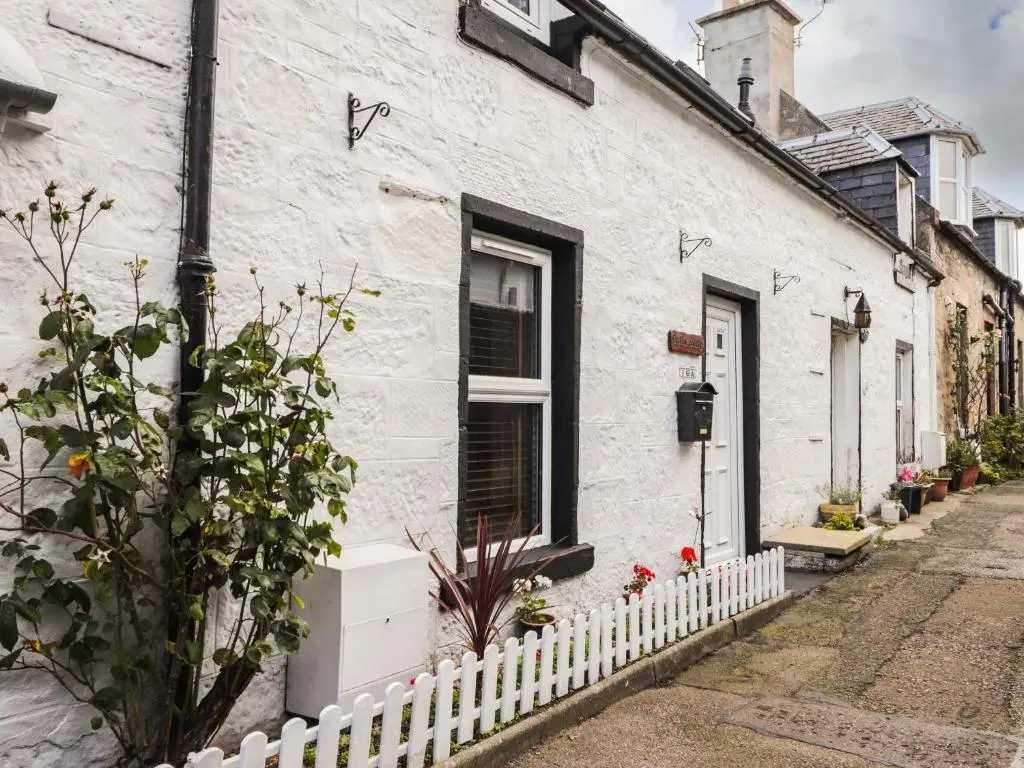 a white house with a white fence in front of it at Griffin Cottage in Nairn