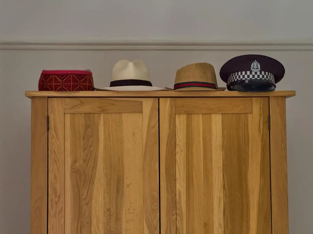 three hats sitting on top of a wooden cabinet at Wester Curr Cottage - Luxury 5-Star Cottage with Private Pool & Hot Tub in Grantown on Spey