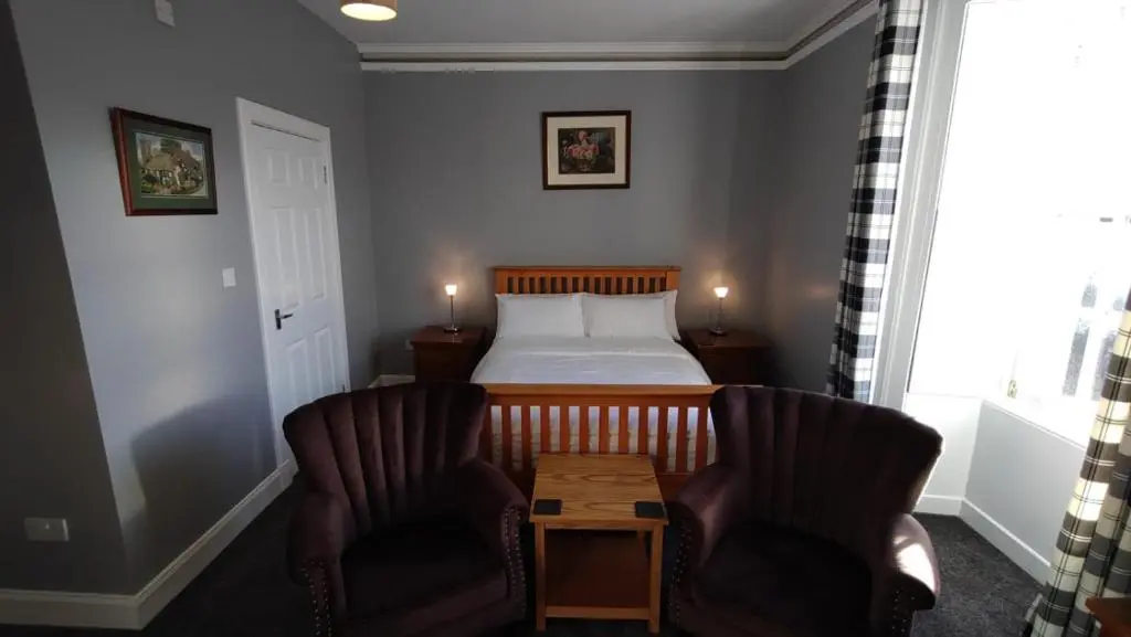 a bedroom with a bed and two chairs and a table at Shandwick House in Tain