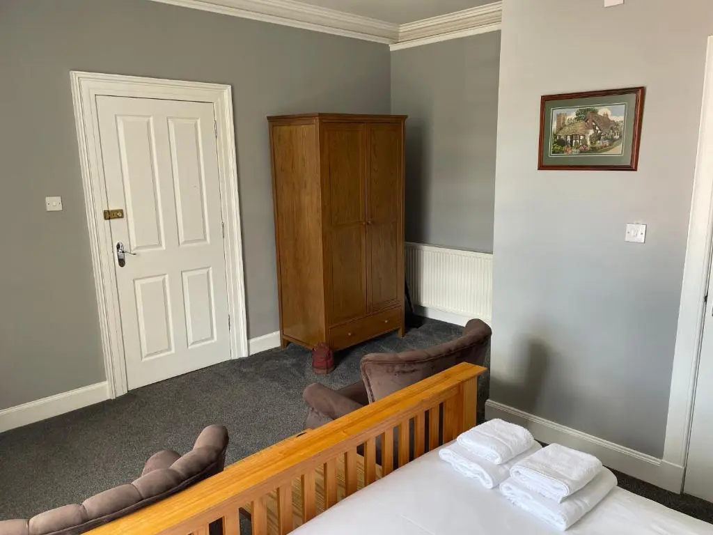 a bedroom with a bed and a dresser and a door at Shandwick House in Tain
