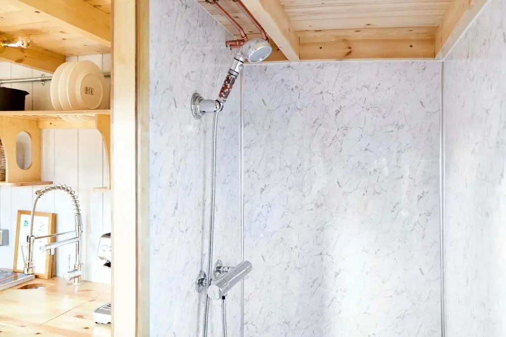 a shower with a glass door in a bathroom at Aileen - Unique tiny house with wood fired roll top bath in heart of the Cairngorms in Ballater