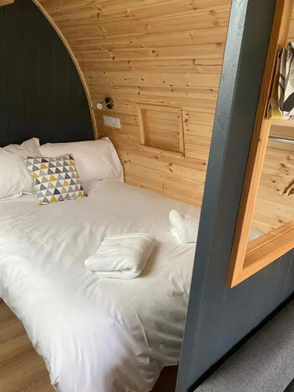 a white bed in a room with wooden walls at Owls Retreat Glamping Pod with Hot tub in Keith