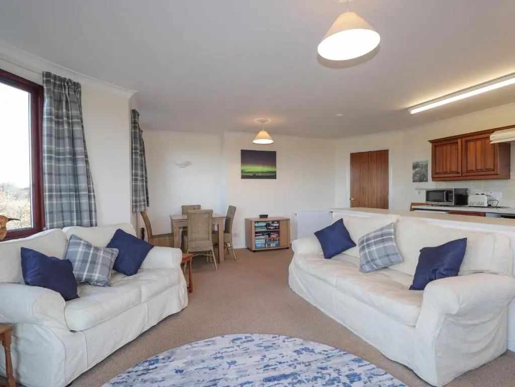 a living room with two white couches and a kitchen at Aurora View in Forres