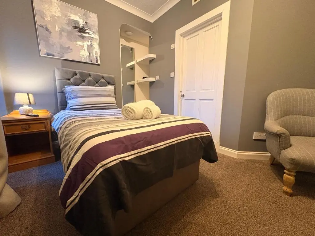 a bedroom with a bed and a chair at Winmar in Inverness
