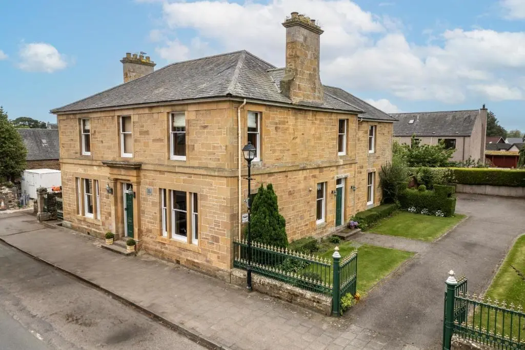 an old brick house with a black fence at The Old Bank House Self Catering Apartment Dornoch in Dornoch