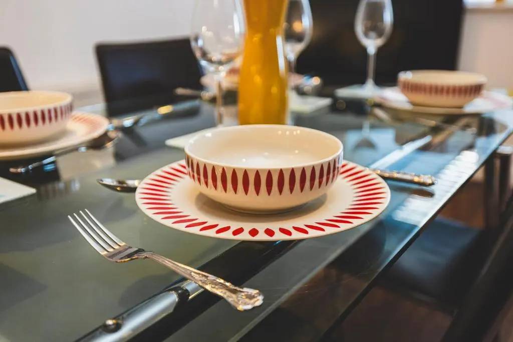 a table with a bowl and a plate with a fork at Bright House with Garden & Patio in Market Town in Inverurie