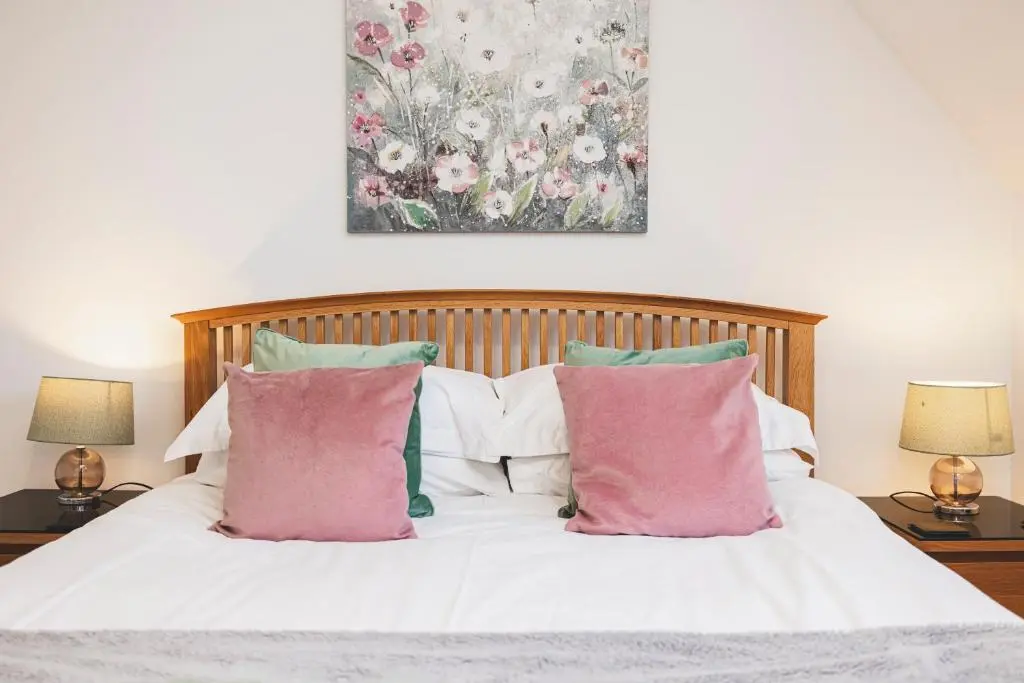 a bed with pink and green pillows on it at Bright House with Garden & Patio in Market Town in Inverurie