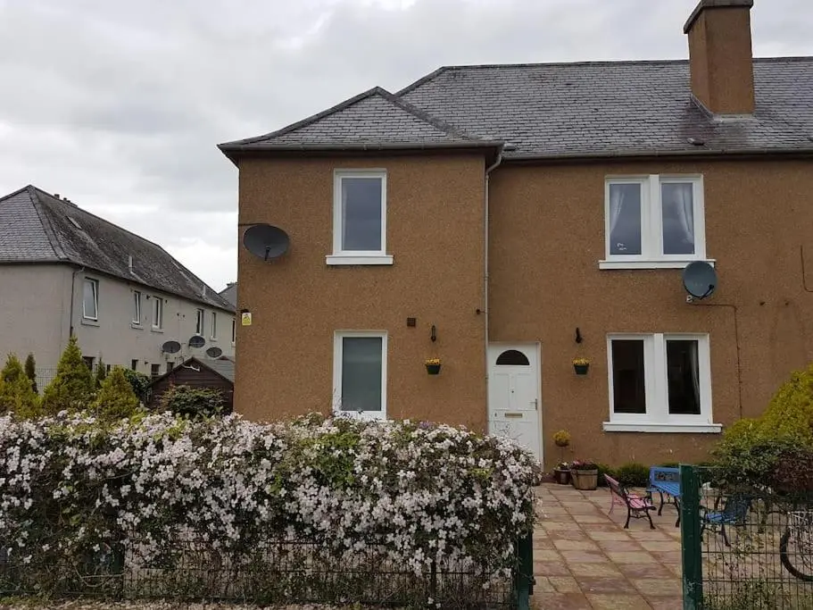 a brown brick house with white windows and a fence at Spacious 2 double bedrooms house for a relaxing stay. in Inverness