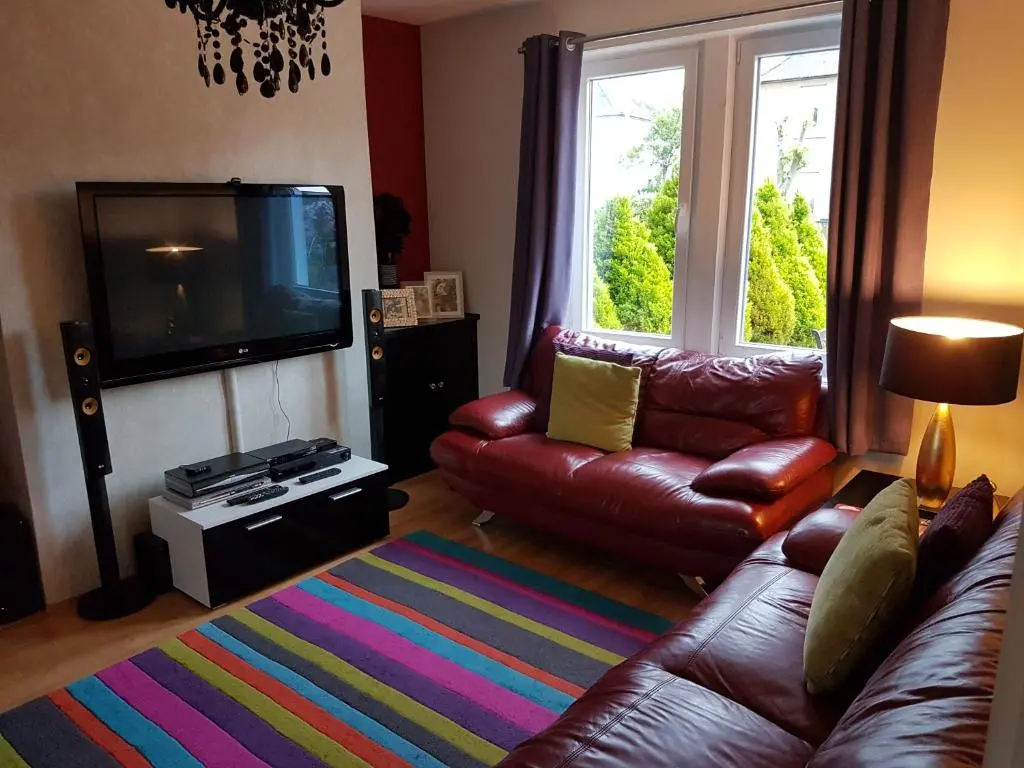 a living room with a leather couch and a television at Spacious 2 double bedrooms house for a relaxing stay. in Inverness