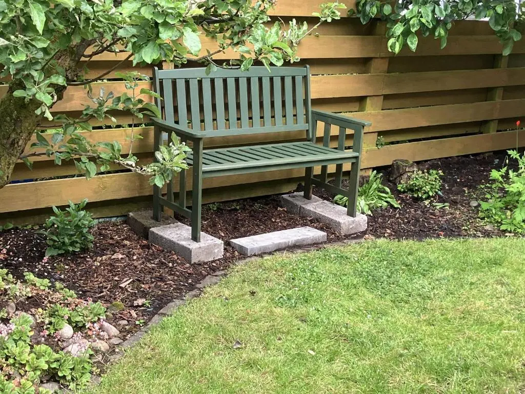 a green bench sitting next to a fence at 3 Dunrobin Street in Tain