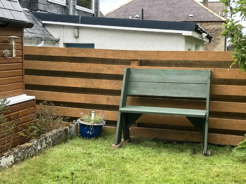 a green bench sitting in front of a fence at 3 Dunrobin Street in Tain