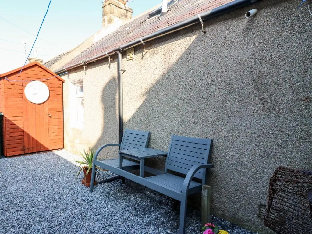 a blue chair sitting next to a building at Seaspray Cottage in Buckie