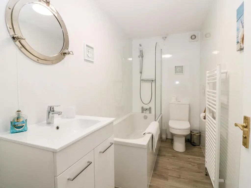 a white bathroom with a sink and a toilet at Seaspray Cottage in Buckie