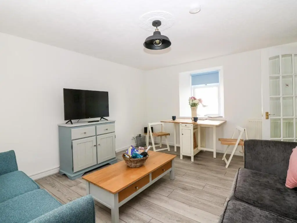 a living room with a couch and a tv and a table at Seaspray Cottage in Buckie