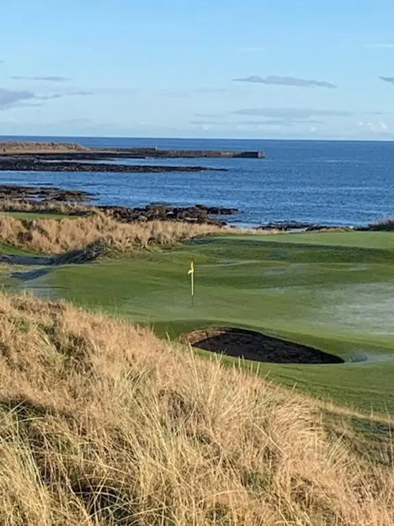 a golf course with the ocean in the background at Balloan Steading East in Dornoch