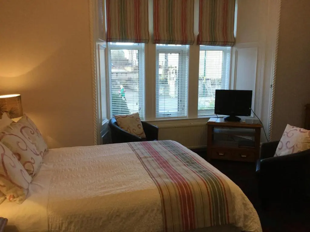 a bedroom with a bed and a television and windows at Moraydale Guest House in Elgin