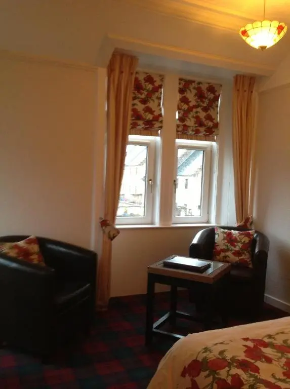a hotel room with a bed and two chairs and a window at Moraydale Guest House in Elgin
