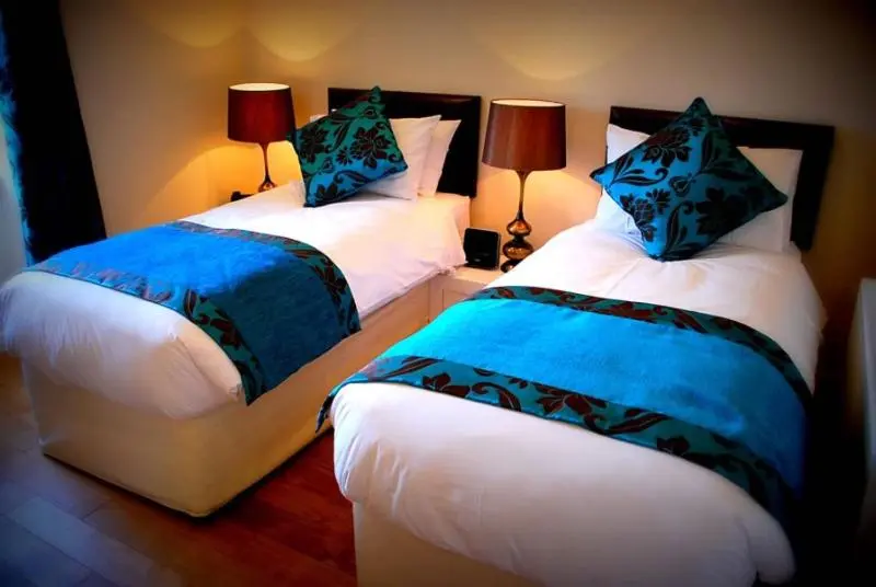 a bedroom with two beds with blue and white sheets at The Aberlour Hotel in Aberlour