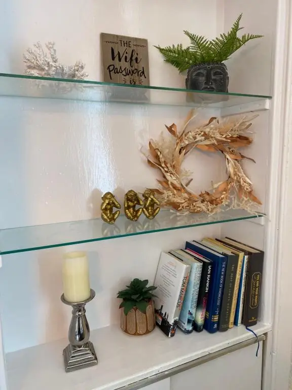 a book shelf with books and a candle and a lamp at Inverness city apartments - Innes in Inverness