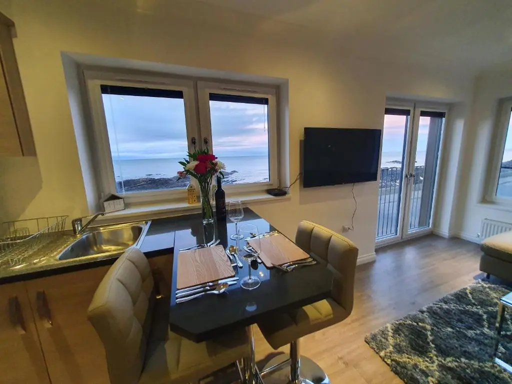 a kitchen with a table with chairs and a sink at 22 Waters Edge Banff in Banff